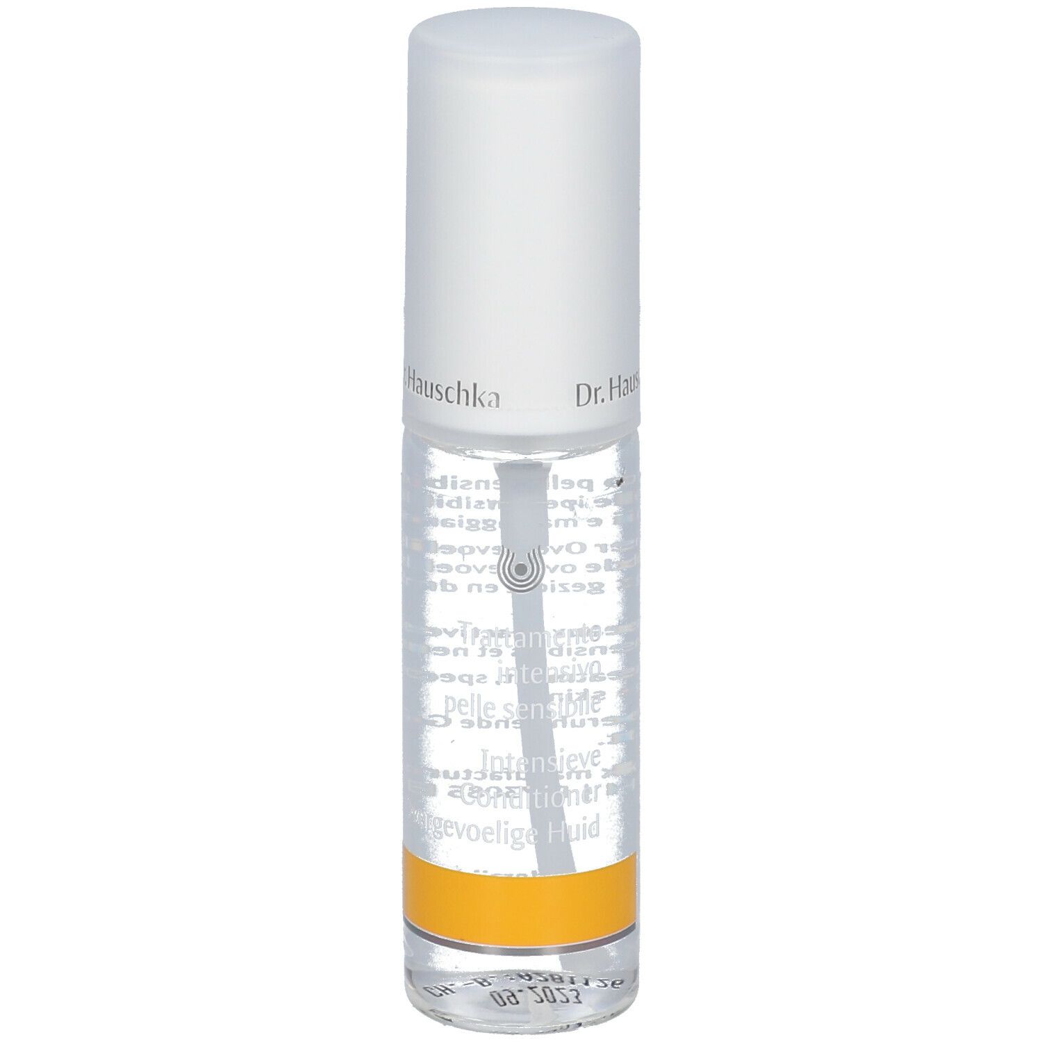 Flacone trasparente con erogatore spray. Scritta: Dr. Hauschka. Etichetta con testo. Striscia gialla in basso.
