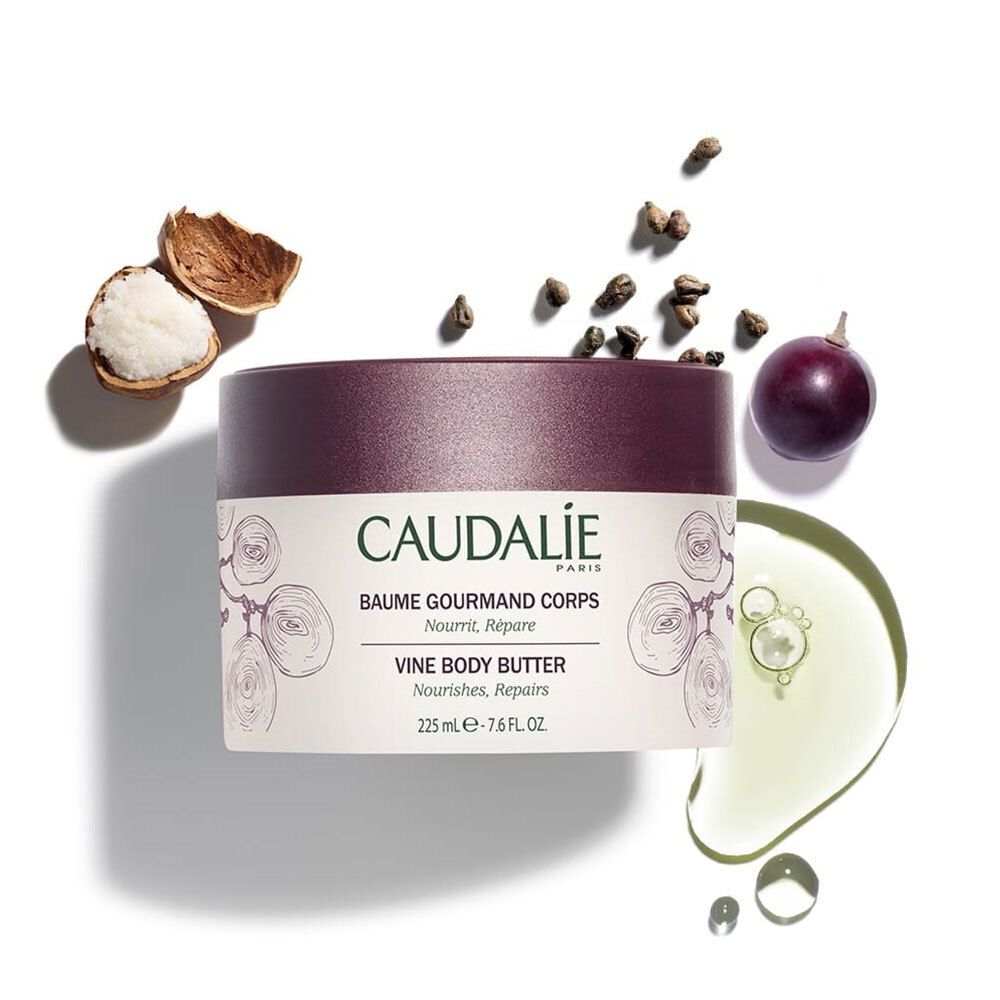 Barattolo di crema con coperchio, accanto uva, semi, olio e noce di karité. Scritta CAUDALIE, VINE BODY BUTTER.