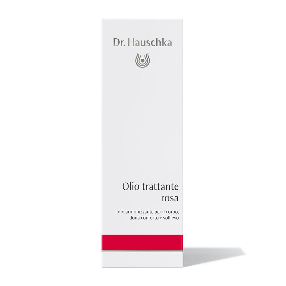Confezione bianca con logo Dr. Hauschka. Testo: Olio trattante rosa. Striscia rossa in basso.