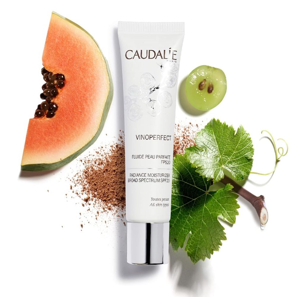 Tubo CAUDALIE Vinoperfect, papaya, uva, foglie e polvere marrone. Nome e dettagli del prodotto sul tubo.