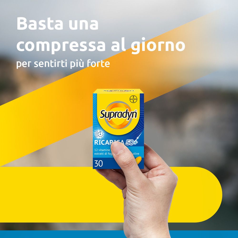 Hand hält Schachtel Supradyn Ricarica 50+. Gelbe und blaue Farben. Text: 30 Tabletten.