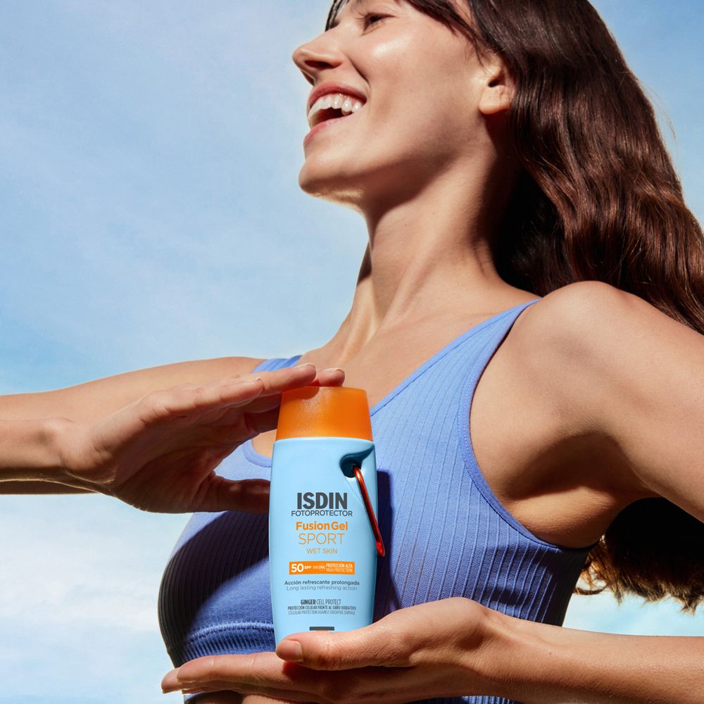 Frau hält eine hellblaue Flasche mit orangefarbenem Deckel. ISDIN Fotoprotector Fusion Gel Sport SPF 50.