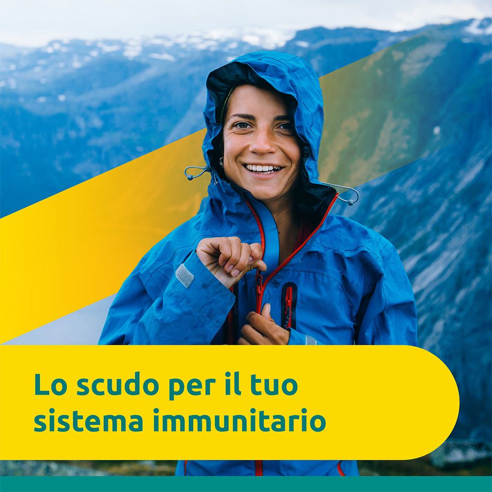 Frau in blauer Jacke vor Berglandschaft. Gelber Balken mit Text: Der Schutz für Ihr Immunsystem.