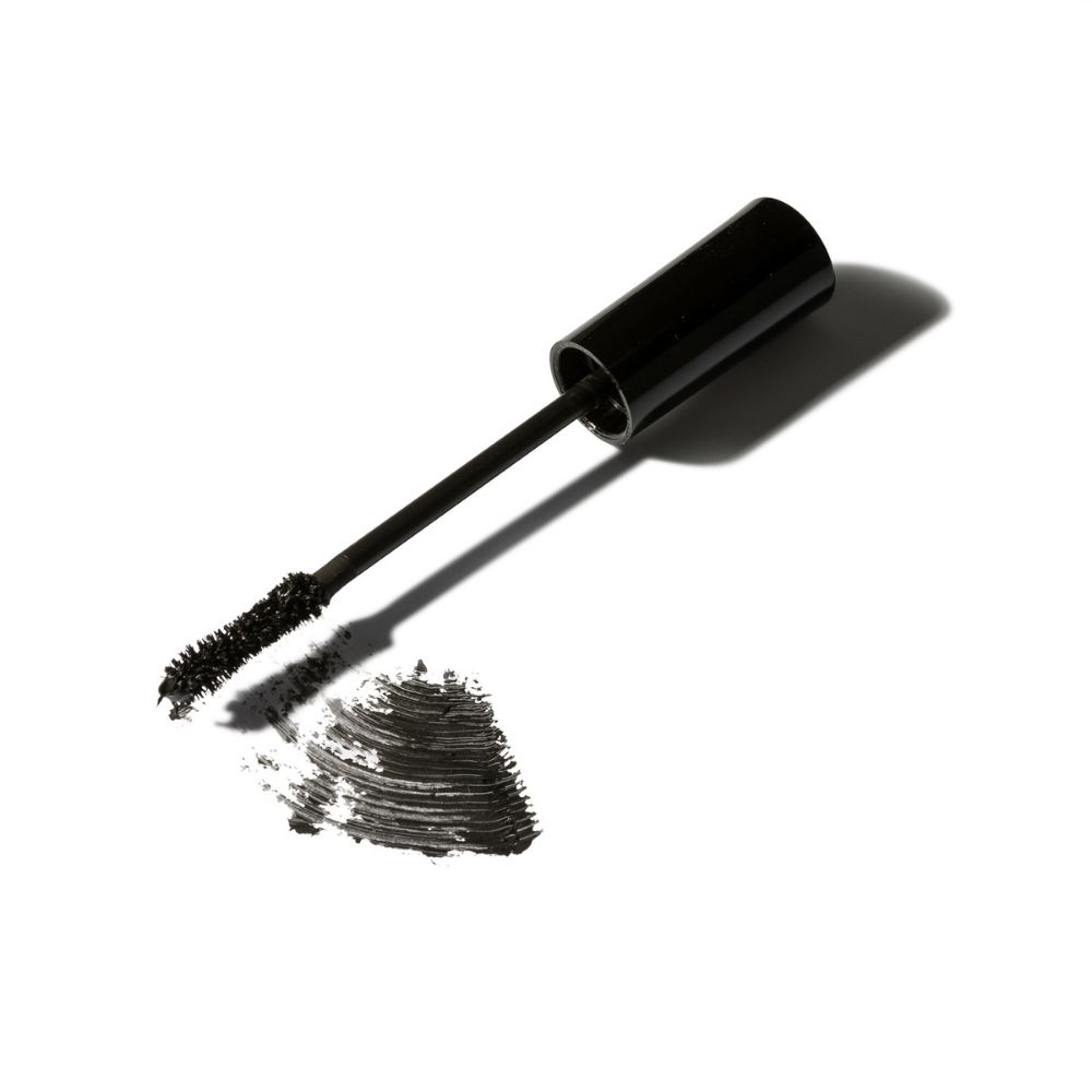 Mascara-Applikator mit schwarzer Textur und einem Klecks auf weißem Grund.
