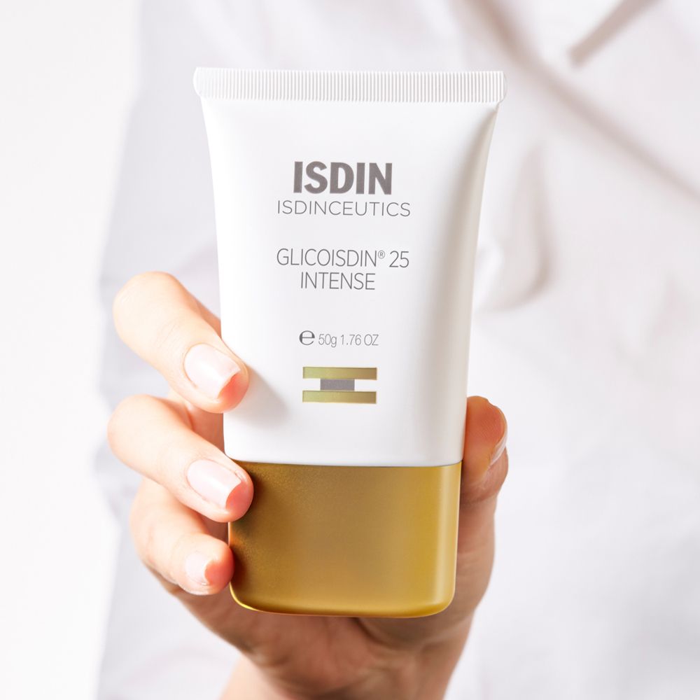 Tubo bianco ISDIN Glicoisdin 25 Intense, base dorata, tenuto in mano. Marchio e nome del prodotto visibili.