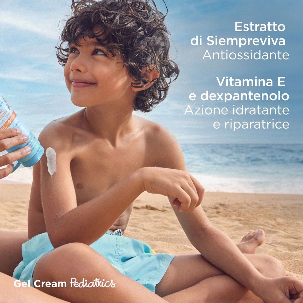 Bambino con crema solare. Contiene estratto, vitamina E e dexpantenolo. Nome prodotto non visibile.