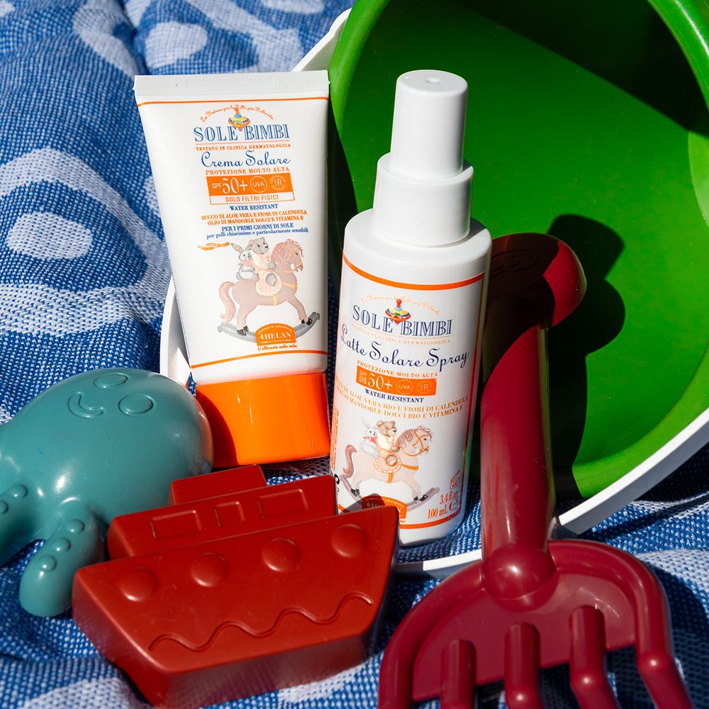 Strandspielzeug und Sonnenschutz. Sonnenspray und Sonnencreme. Aufdruck: Sole Bimbi, SPF 50+.