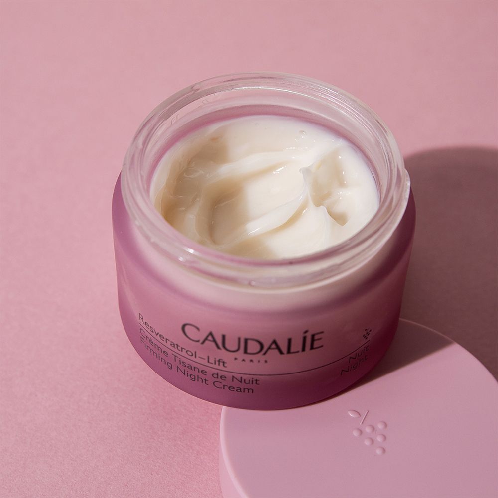 Offener rosa Tiegel mit Creme. Aufschrift CAUDALÍE, Resveratrol-Lift, Crème Tisane de Nuit, Firming Night Cream.