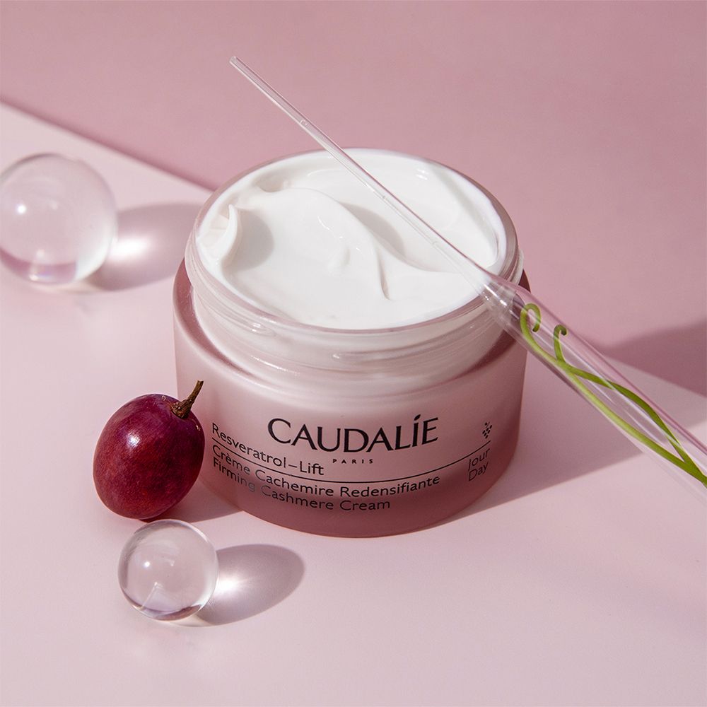 Pot de crème rempli, à côté raisin et spatule. Inscription: CAUDALIE.