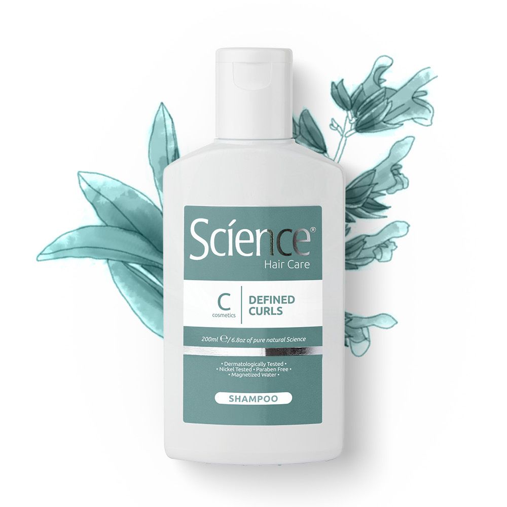 Flacone di shampoo bianco con etichetta verde e illustrazione floreale. Scritta: Science Hair Care, Defined Curls, Shampoo. Dermatologicamente testato.