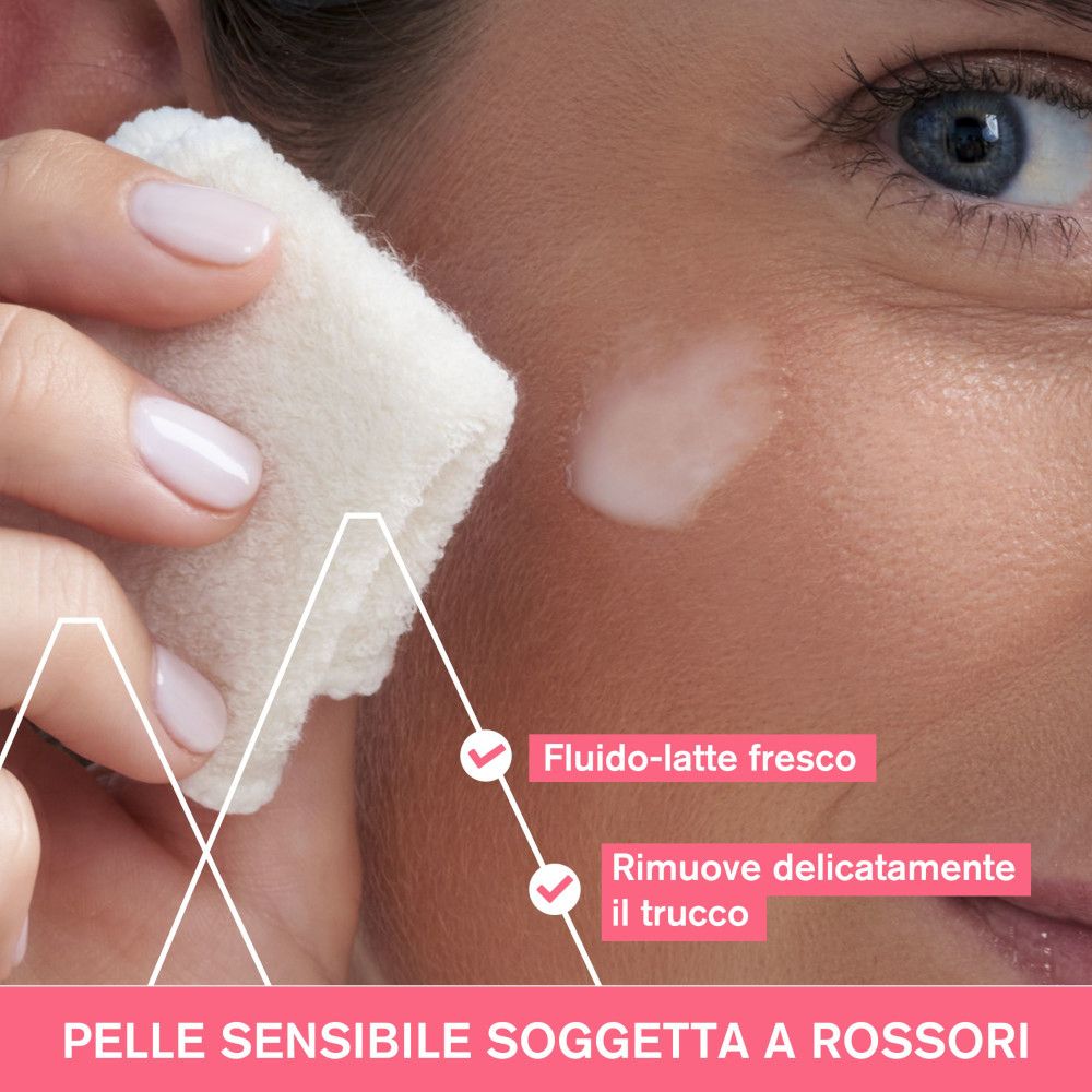 Primo piano di una donna che si pulisce il viso con un batuffolo di cotone. Testo: Fluido-latte fresco, rimuove delicatamente il trucco.