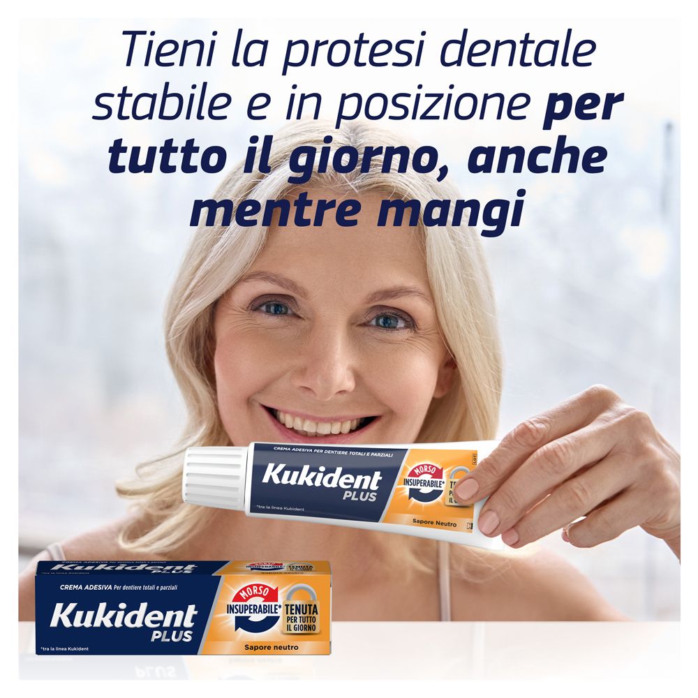 Frau hält Kukident Plus Tube. Tube und Schachtel liegen auf dem Tisch. Text: Tieni la protesi...