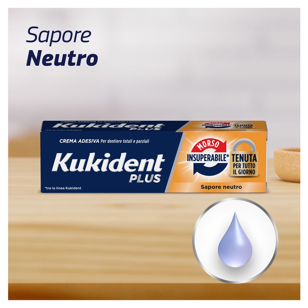 Kukident Plus Schachtel auf Holz. Text: Crema adesiva per dentiere totali e parziali. Sapore Neutro.