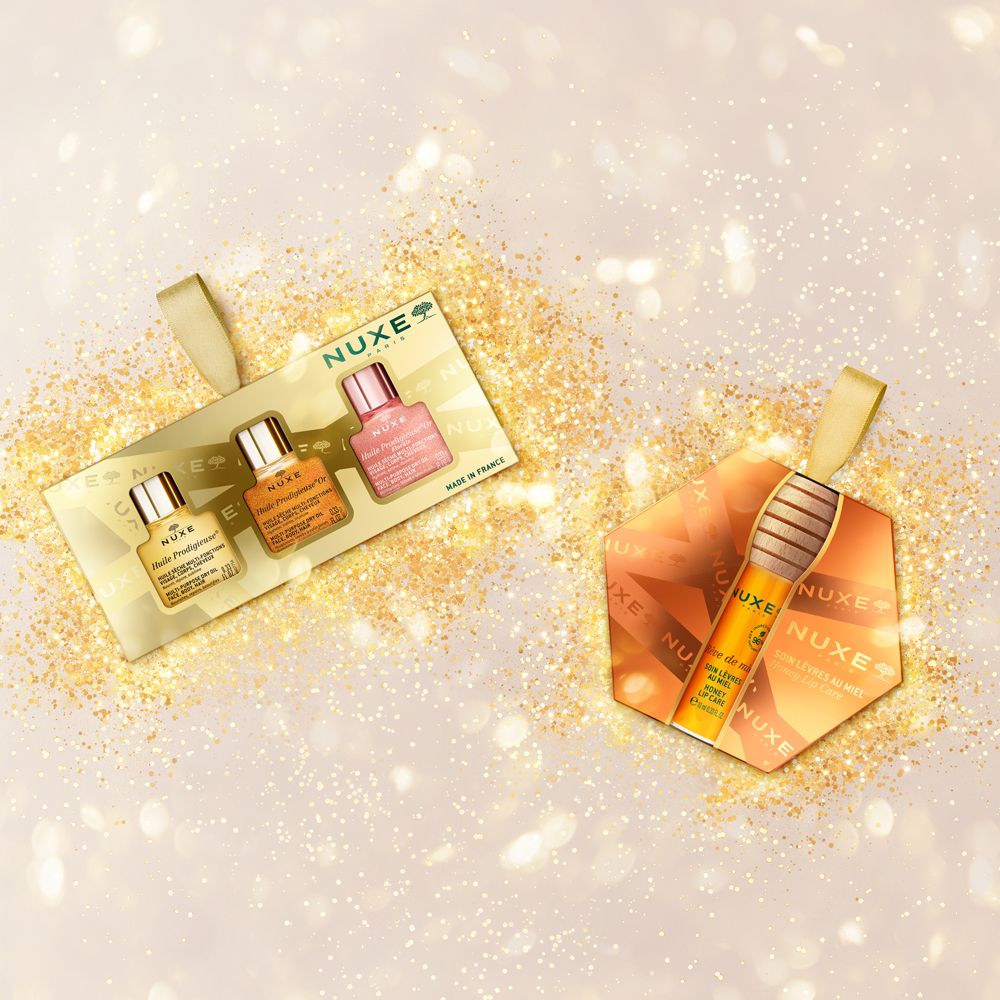Set regalo Nuxe con tre flaconi in miniatura gialli, arancioni e rosa.