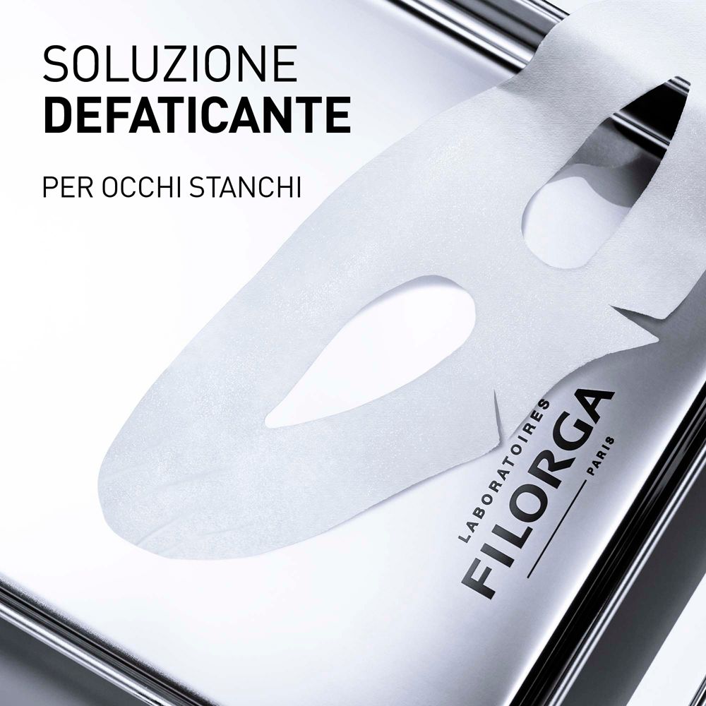 Primo piano di una maschera occhi su un vassoio. Testo: SOLUZIONE DEFATICANTE, PER OCCHI STANCHI. Marchio: FILORGA PARIS.