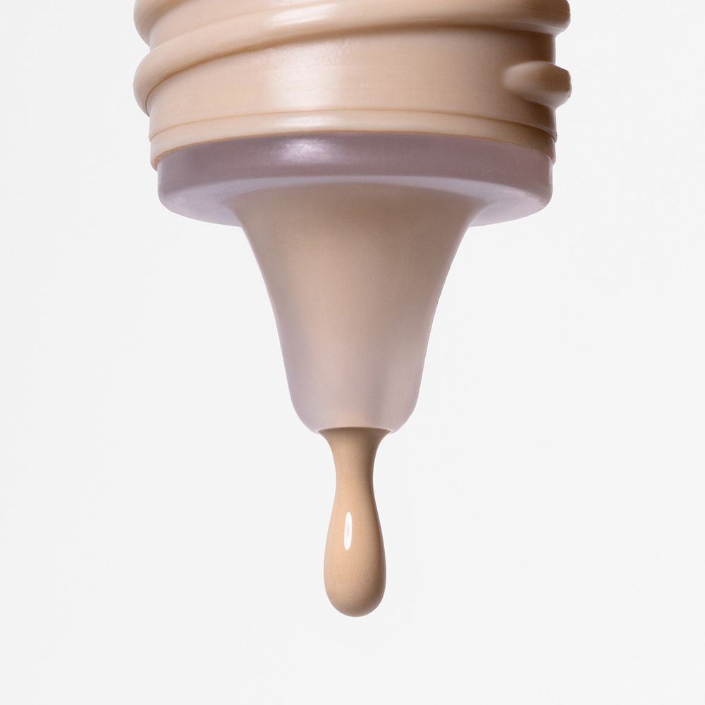 Liquido beige che gocciola da un applicatore.