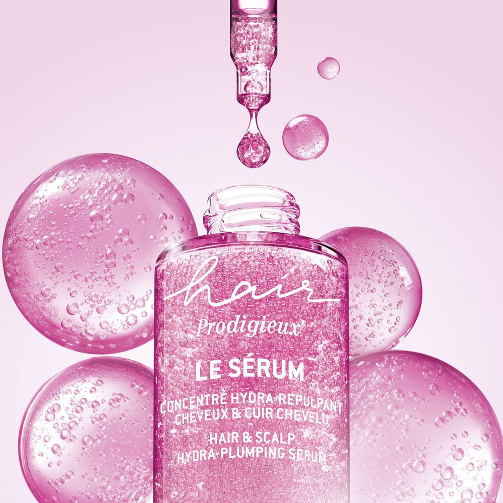 Flacone di siero per capelli, etichettato "Hair Prodigieux Le Sérum", con contagocce e bolle rosa.