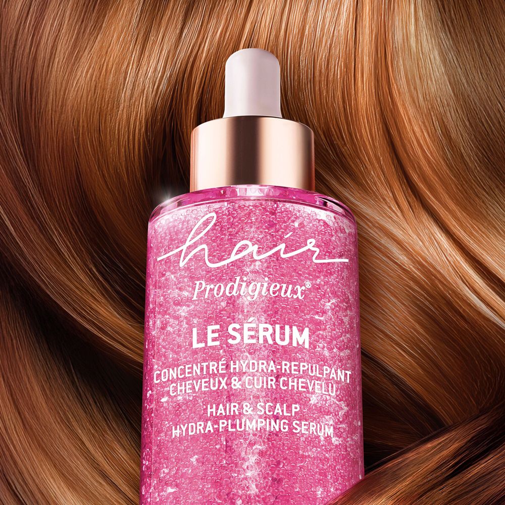 Flacone di siero rosa con contagocce, circondato da capelli castani.