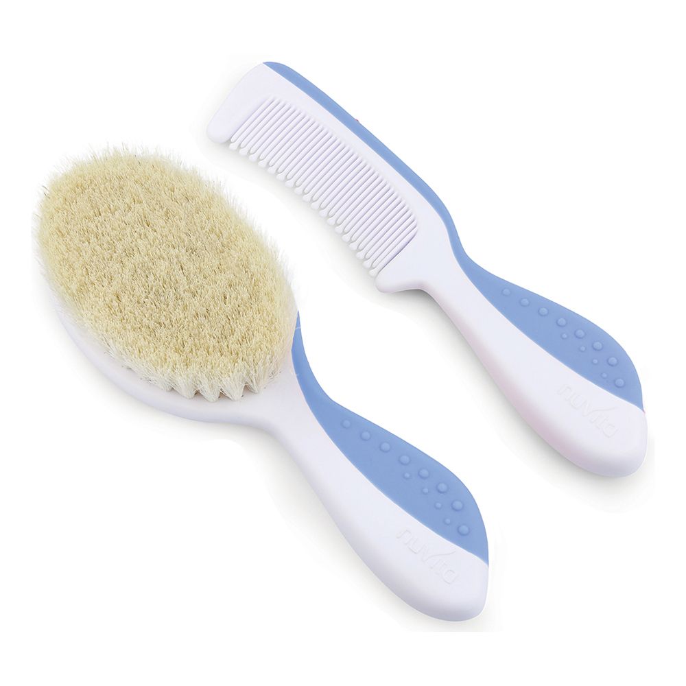 Set spazzola e pettine per neonati. Spazzola con setole chiare, manico bianco e blu. Pettine con denti bianchi, manico blu. Entrambi affiancati.