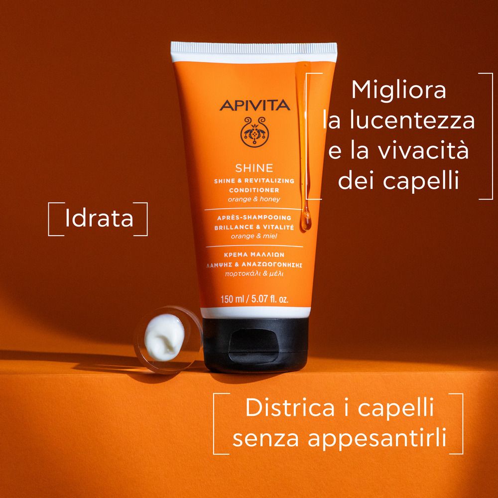 Orange Tube mit schwarzem Deckel. Text: APIVITA SHINE Conditioner. Zusätzlicher Text in Italienisch. Produkt und Tropfen.