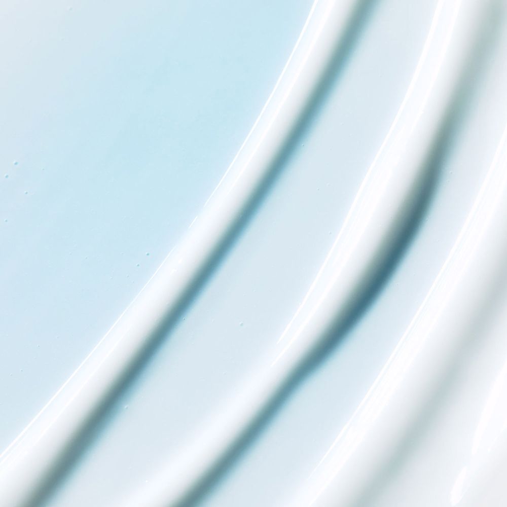 Gros plan de crème blanche avec des lignes ondulées sur fond bleu. Texture du masque hydratant.
