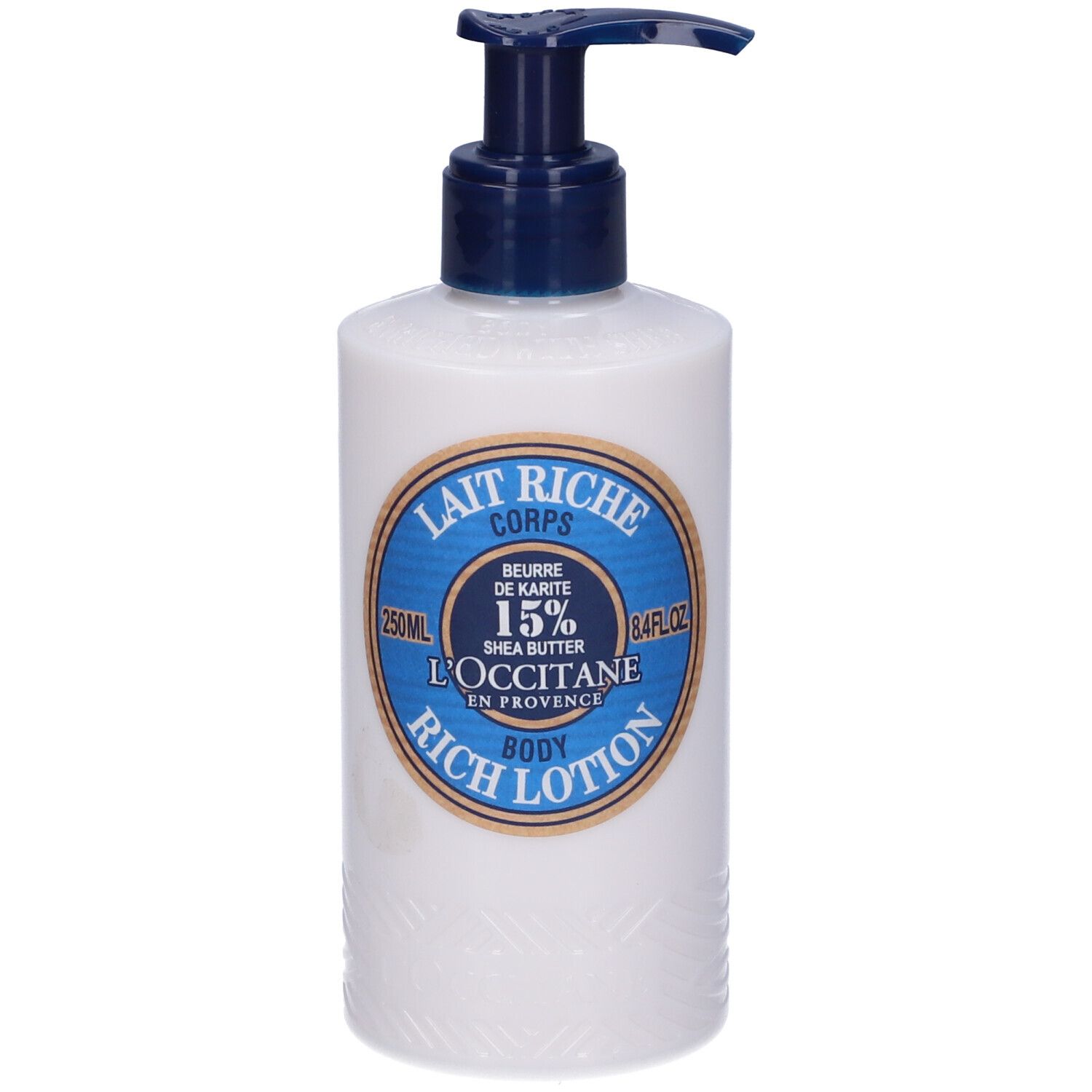 Flacone bianco con erogatore blu. Etichetta: Lait Riche Corps, Burro di Karité 15%, L'Occitane.