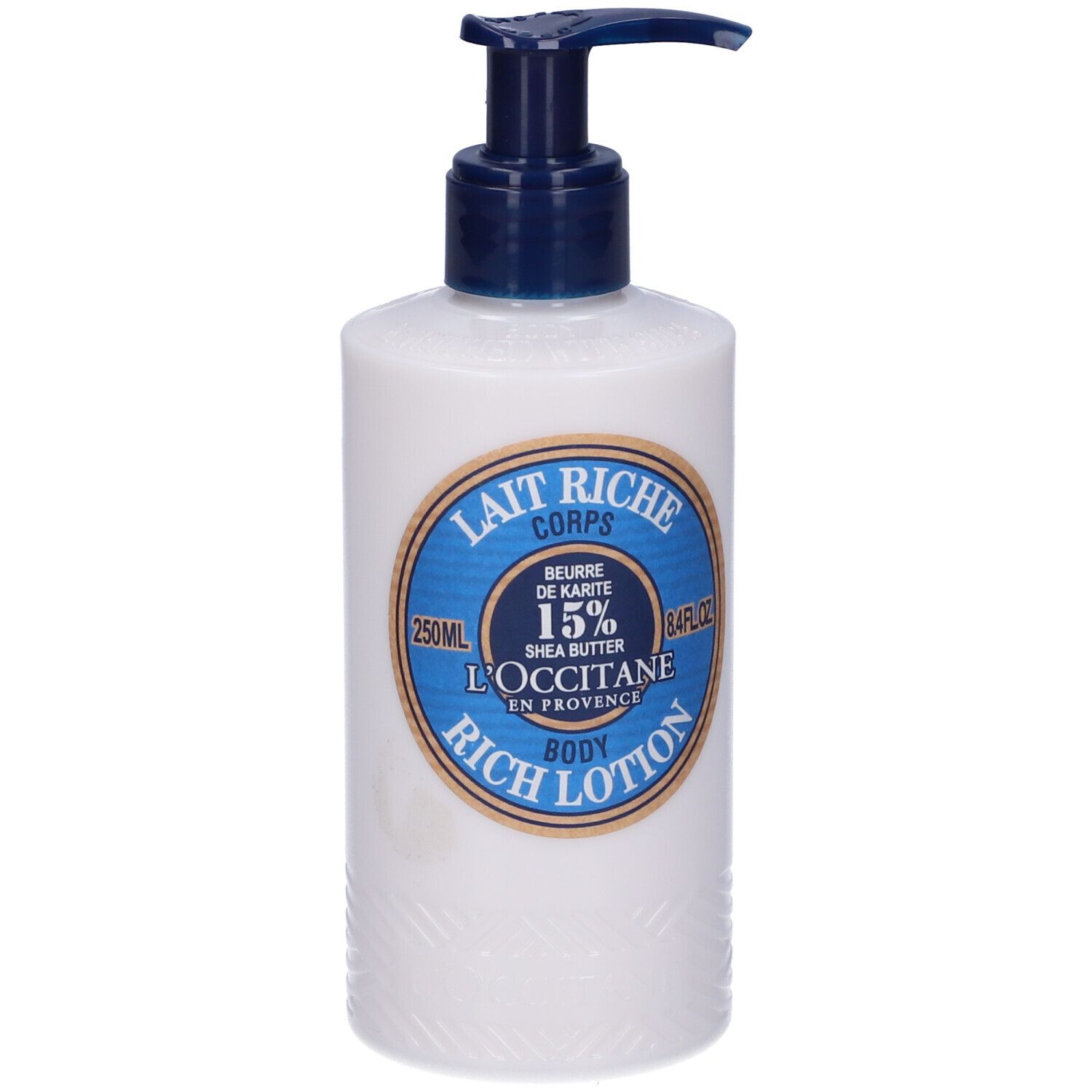 Flacone bianco con erogatore blu. Etichetta: Lait Riche Corps, Burro di Karité 15%, L'Occitane.