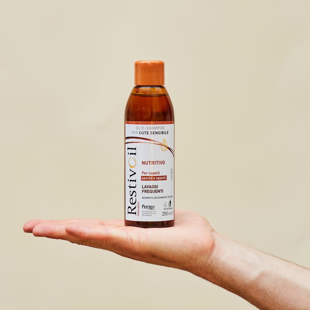 Shampoo-Flasche auf einer Handfläche. Braune Flasche mit orangefarbenem Deckel, Produktinformationen.