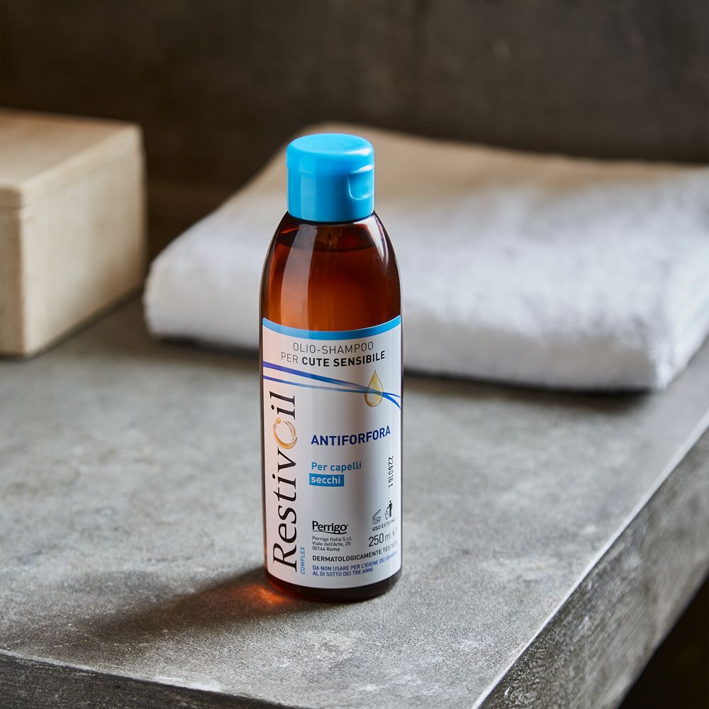 Flacone di shampoo all'olio Restivoil. Bottiglia marrone, tappo blu. Su una superficie. 250ml.