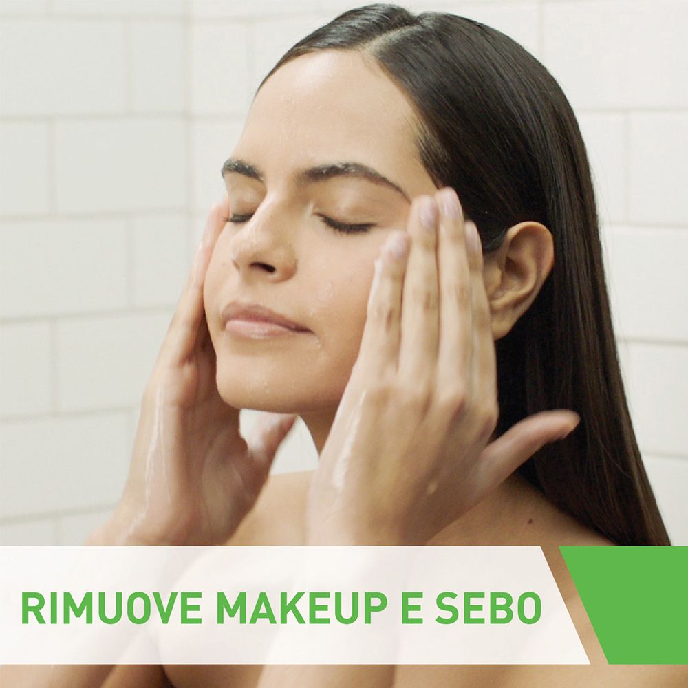 Donna che si lava il viso. Lozione detergente bianca e schiumosa. Testo: Rimuove trucco e sebo.