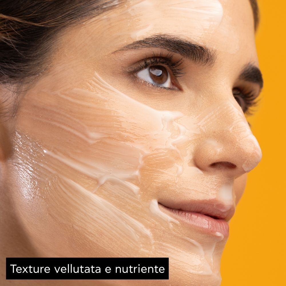 Viso di una donna con maschera facciale. Testo: Texture vellutata e nutriente.