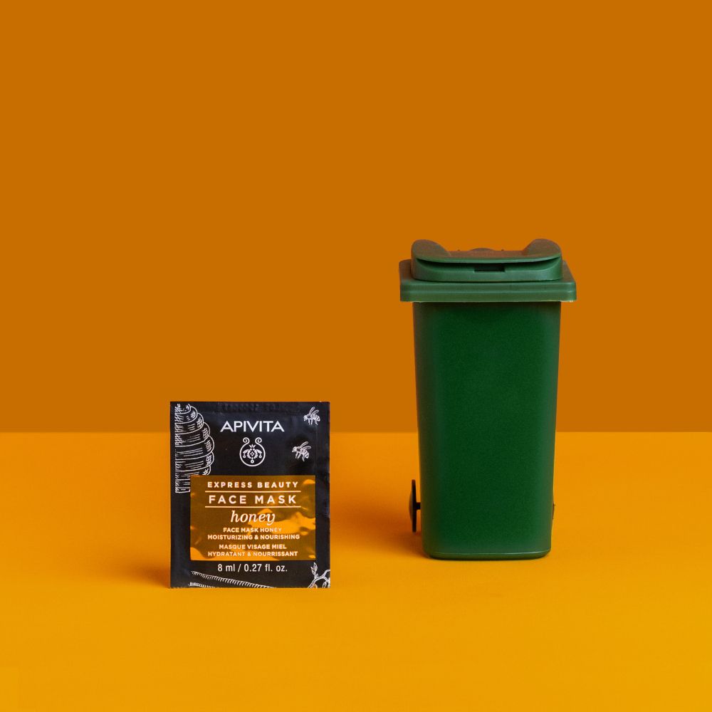 Bustina APIVITA EXPRESS BEAUTY Face Mask Honey accanto a un bidone verde. Testo: honey, 8 ml / 0.27 fl. oz.