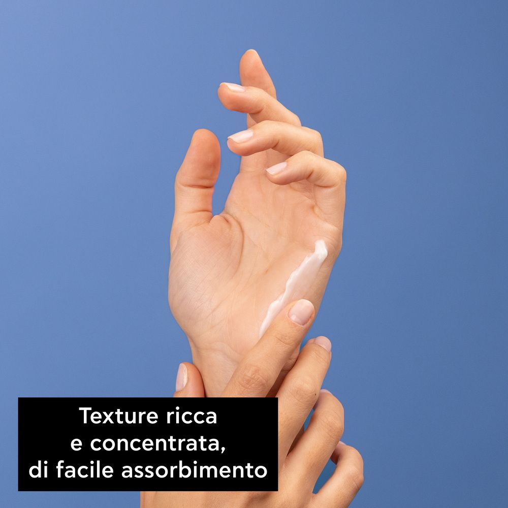 Mani con crema su sfondo blu. Testo: Texture ricca e concentrata, di facile assorbimento.