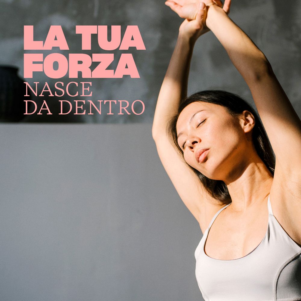 Frau mit erhobenen Armen. Grauer Hintergrund. Text: LA TUA FORZA NASCE DA DENTRO.
