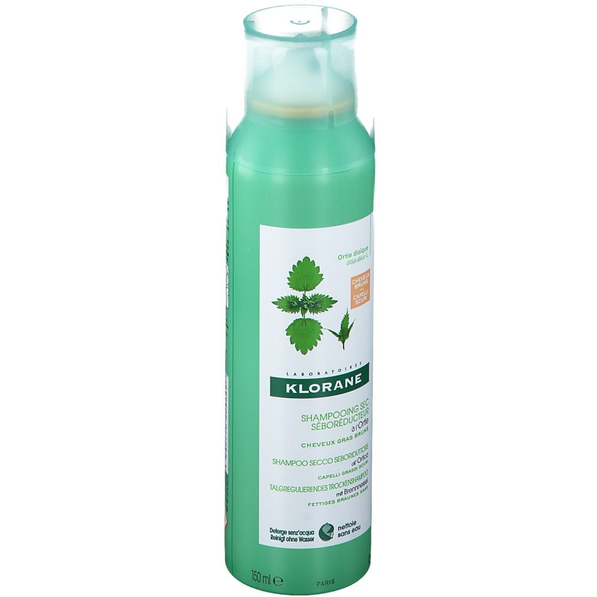 Flacone spray verde con etichetta bianca. Scritta: Klorane, shampoo secco all'ortica. Illustrazione di foglie di ortica.