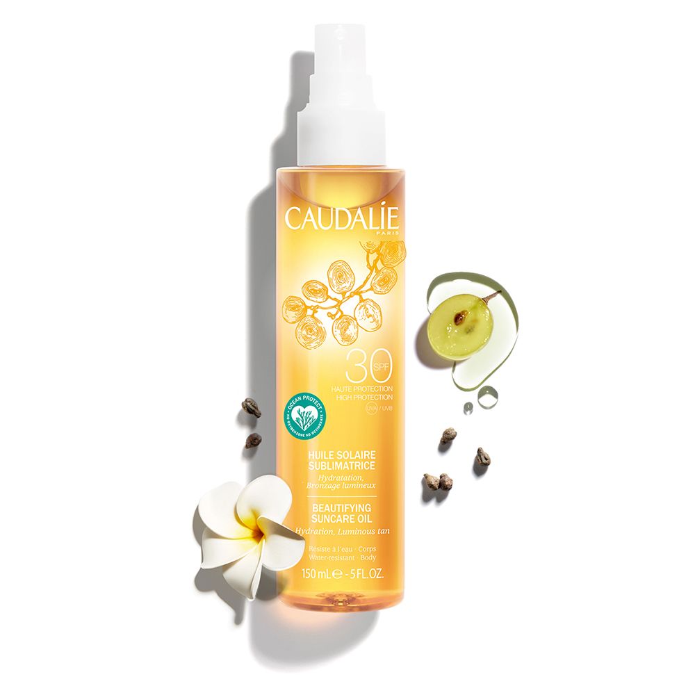 Caudalie Sonnenöl LSF 30 Flasche mit Traube, Kernen und Blüte. Gelbe Flüssigkeit, weißer Sprühkopf. Aufschrift: Huile Solaire.