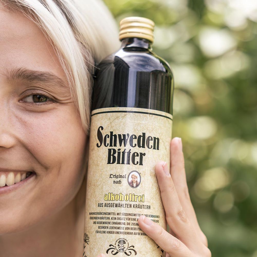 Frau hält eine Flasche Schweden Bitter Original, alkoholfrei, mit Etikett und goldenem Verschluss.