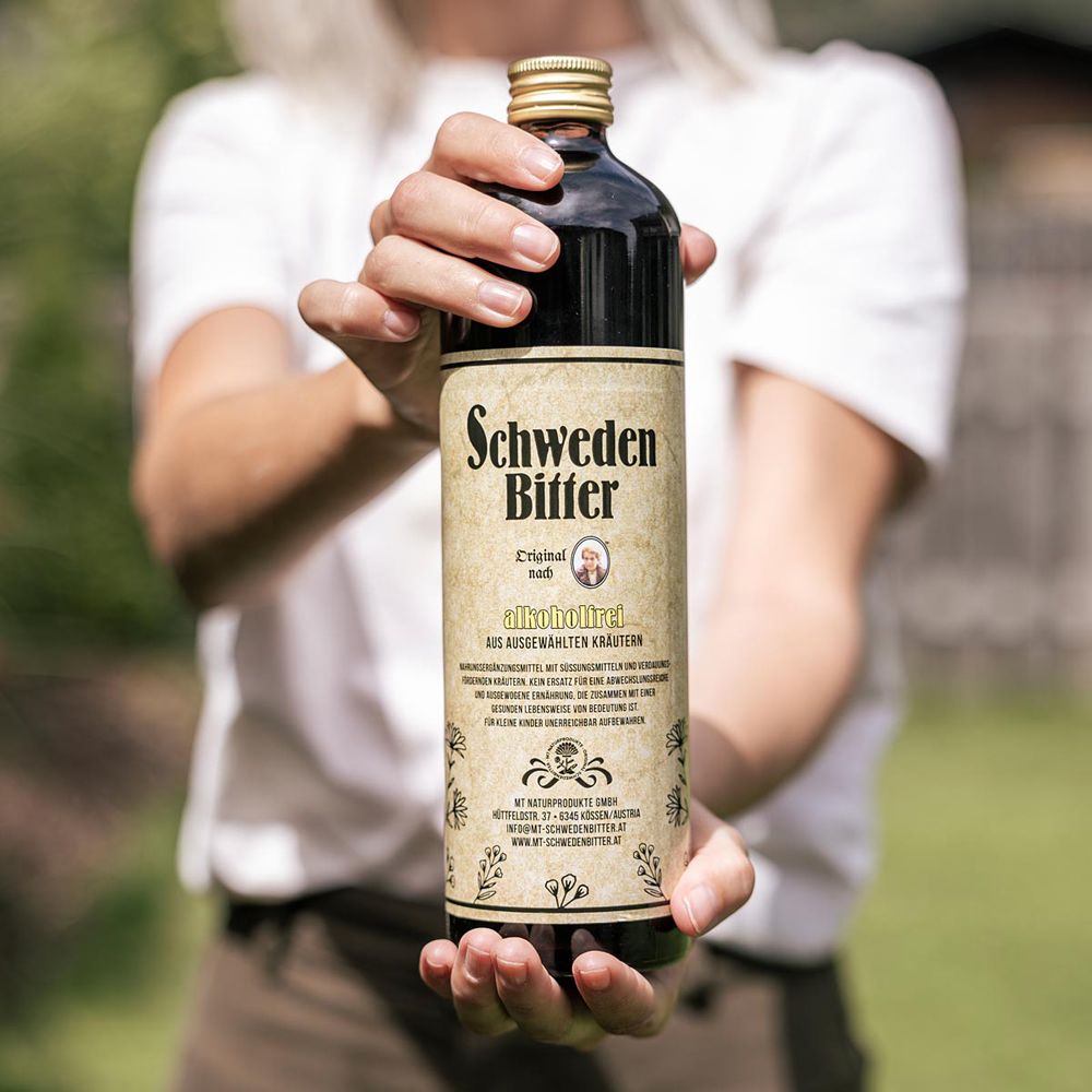 Frau hält eine Flasche Schweden Bitter Original, alkoholfrei, mit Etikett und goldenem Verschluss.