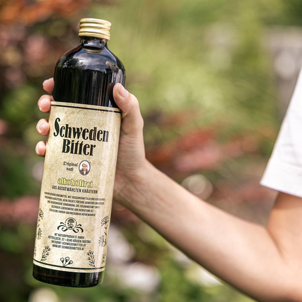 Hände halten eine Flasche Schweden Bitter Original, alkoholfrei, mit Etikett und goldenem Verschluss.