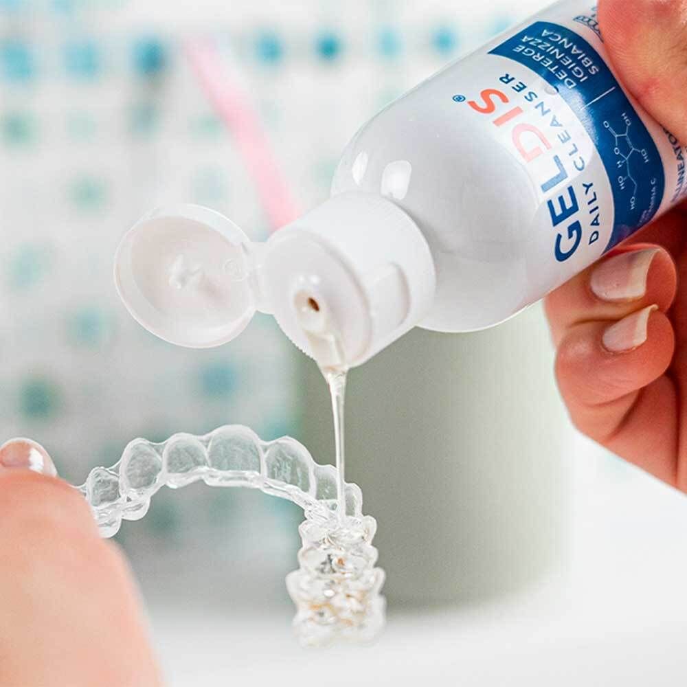 GELDIS Daily Cleanser versato su un allineatore. Flacone e allineatore visibili.