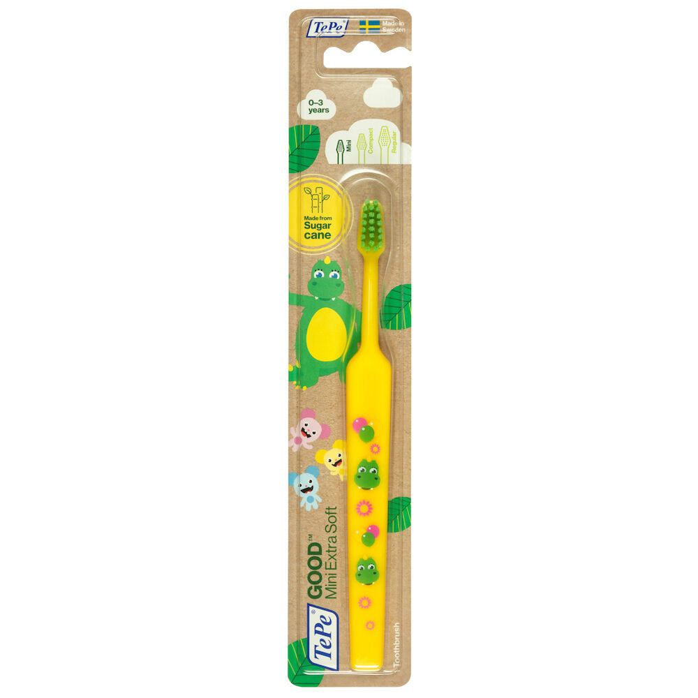 Spazzolino giallo per bambini con testina verde, in confezione. Illustrazioni e nome del prodotto stampati.