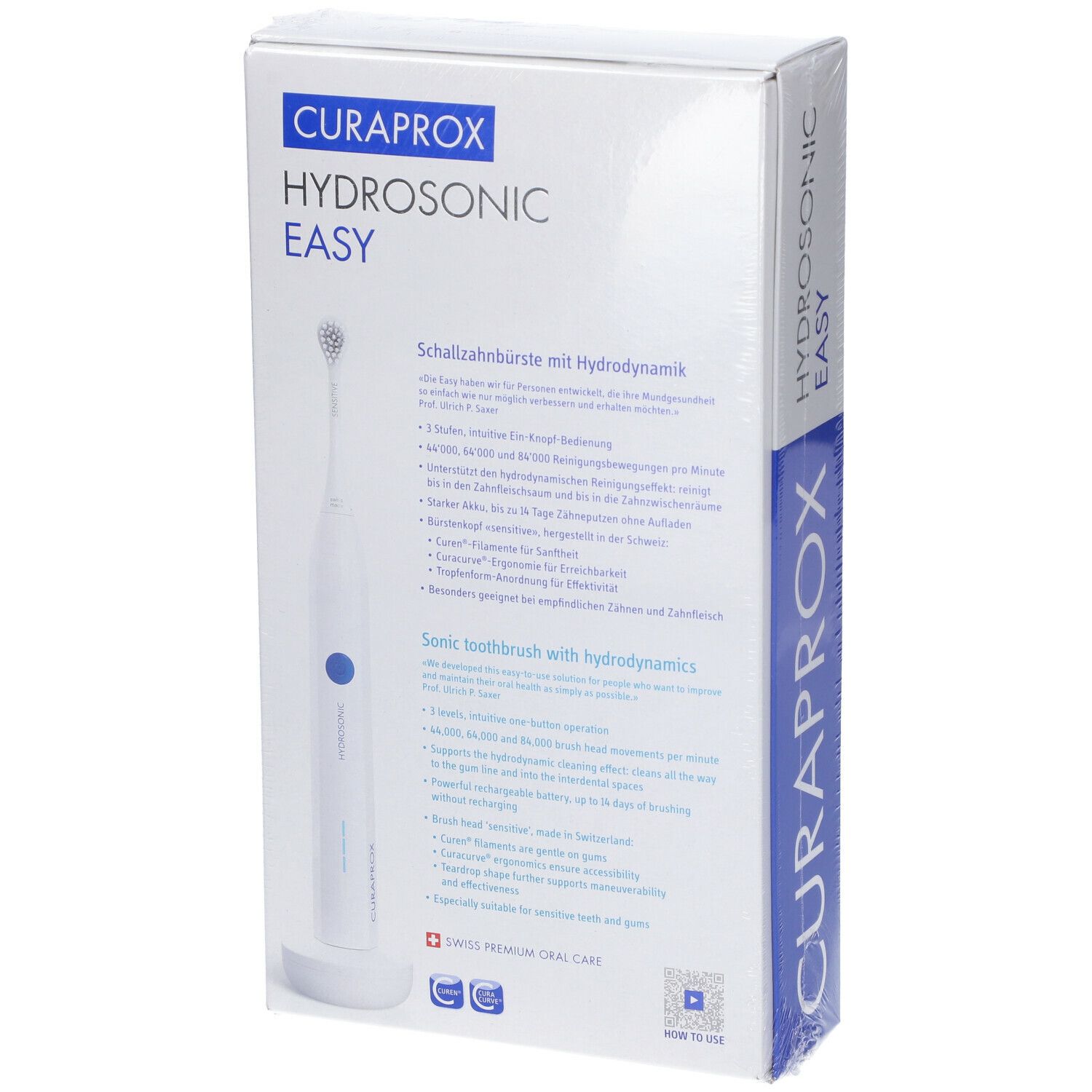 Confezione dello spazzolino sonico. Bianco con accenti blu. Testo: CURAPROX HYDROSONIC EASY. Descrizione in tedesco e inglese.