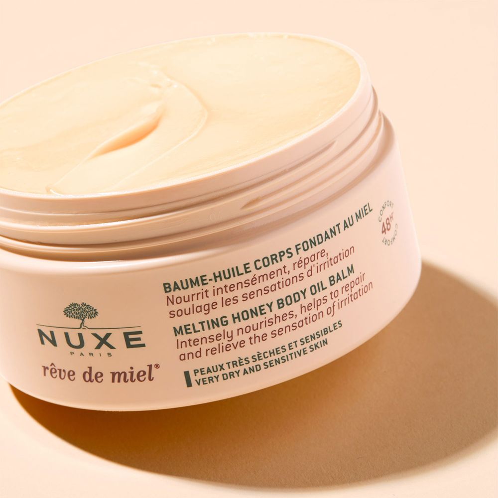 Barattolo di crema aperto con coperchio marrone. Sostanza cremosa giallastra. Scritta: NUXE Rêve de Miel, Melting Honey Body Oil Balm.