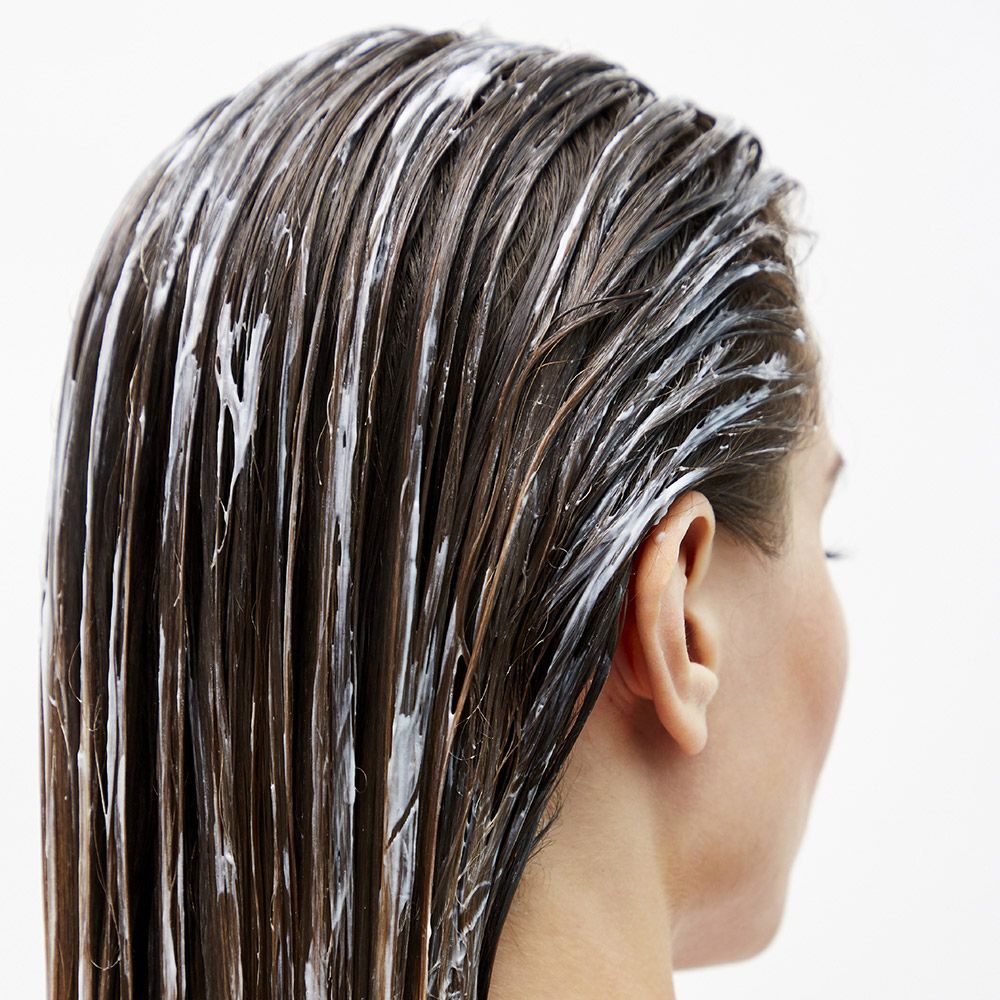 Rückansicht einer Person mit nassen Haaren, bedeckt mit weißer Creme.