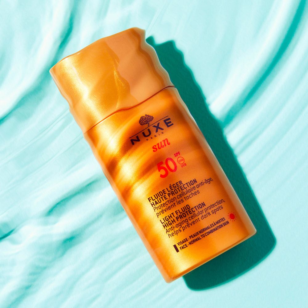 NUXE Sun Light Fluid SPF50. Flacone arancione su sfondo blu. Testo: Sun, 50 SPF, Fluide Léger, Alta Protezione. Per pelli normali e miste.