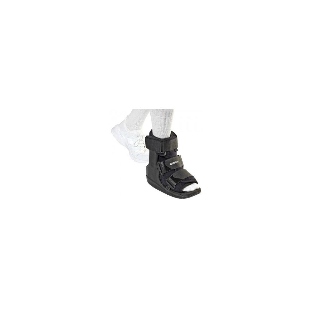 Tutore Walker nero su gamba. Chiusure a strappo e punta aperta. Accanto, una scarpa bianca.