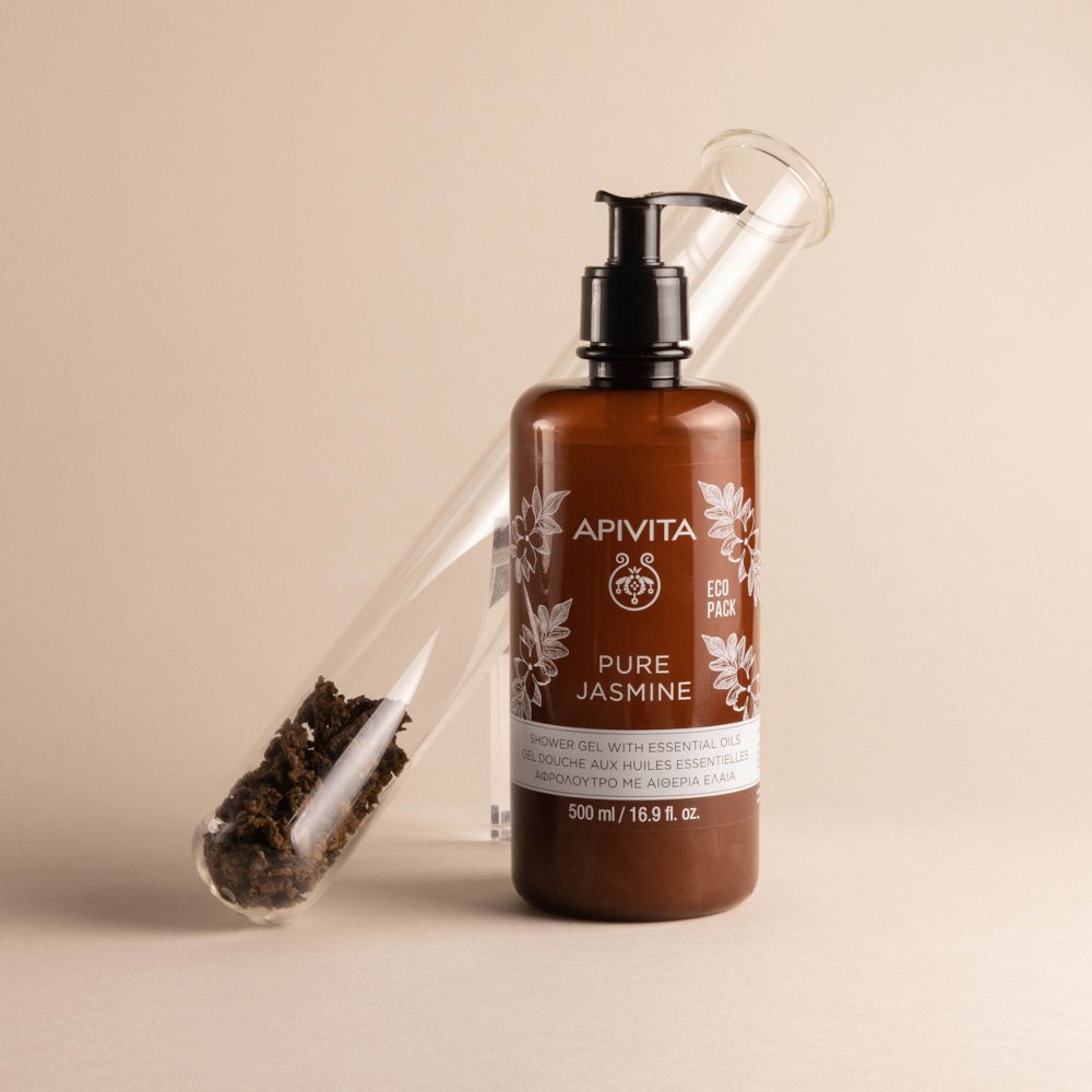 Flacone marrone con dosatore nero. APIVITA Pure Jasmine. Accanto a una provetta.