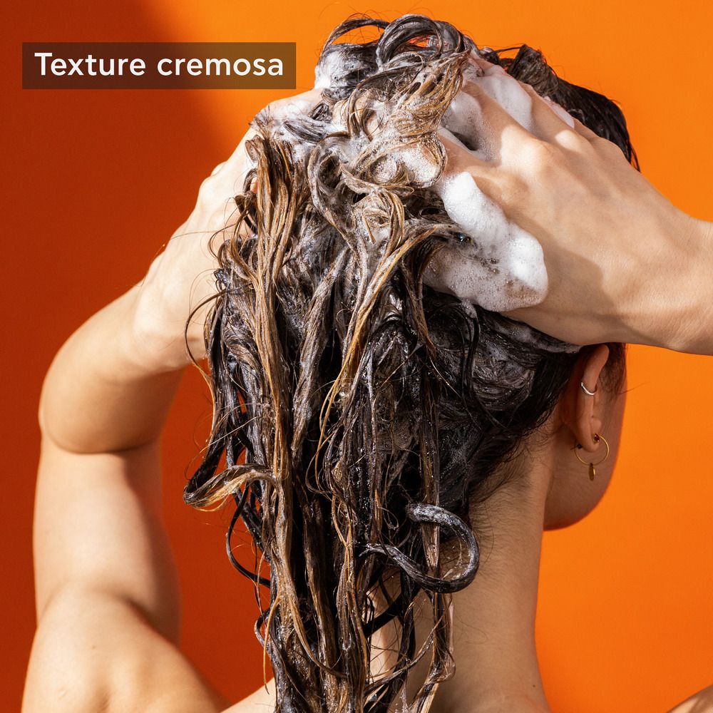 Mani che lavano i capelli con lo shampoo. Testo: Texture cremosa.