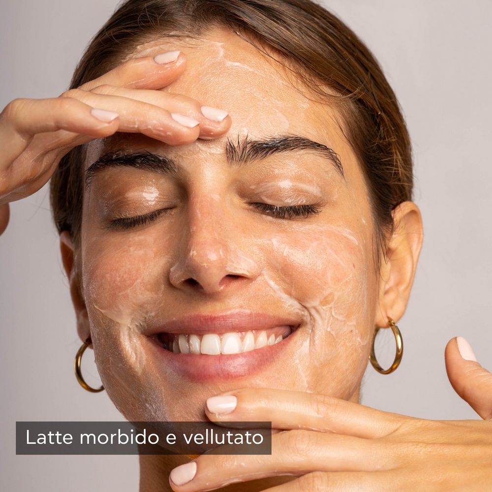 Donna con occhi chiusi, viso coperto di latte detergente. Testo: Latte morbido e vellutato.