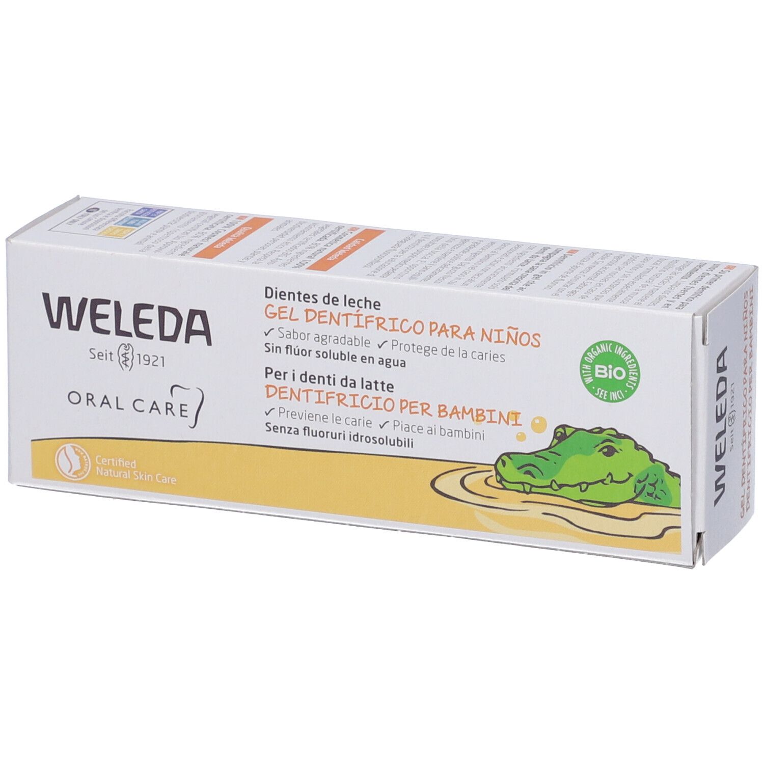 Confezione di gel dentifricio Weleda. Testo: "Oral Care", "Gel dentifrico para niños". Certificazione bio. Illustrazione di un coccodrillo. Colori giallo e bianco.